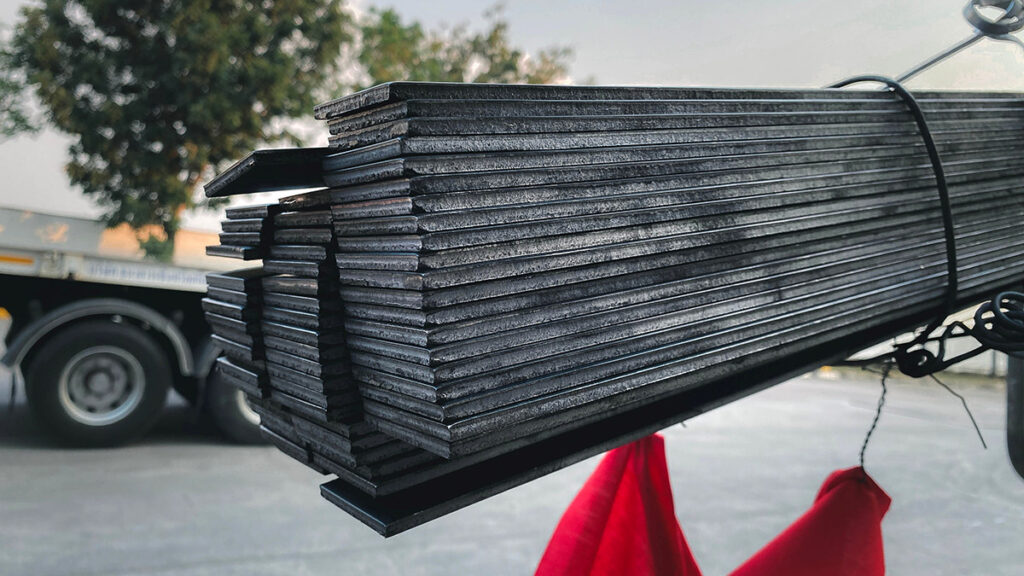 Flat, rectangular steel bars stacked in the flatbed of a truck.